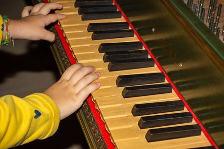 Hand of Child Playing Medieval Harpsichord in a Castle in Italy on Blurred Background