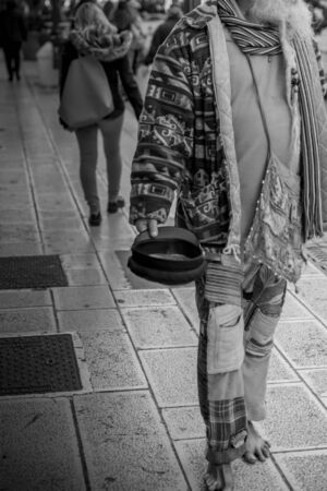 Old Man in Colorful Clothes asking for Alms on the street during Christmas Period in Taranto, South of Italyの写真素材