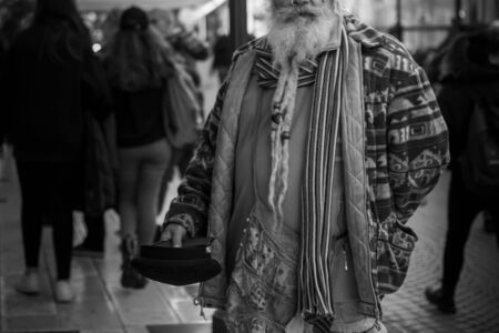 Old Man in Colorful Clothes asking for Alms on the street during Christmas Period in Taranto, South of Italyの写真素材