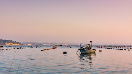 Small Boat Moored in Vicinity of Mussil Plantation In Italy. Mar Piccolo VIew at Sunset in Taranto, Italyの写真素材
