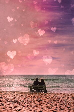 Romantic couple on the beach at colorful sunset on harts background. Perfect tropical sunset landscape, exotic nature view. Happy romantic couple enjoying beautiful sunset at the beach. Saint Valentine 's Day celebrationの写真素材