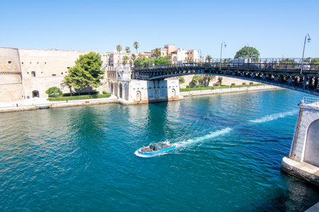 small boat that cross the swing bridge in front of the aragonian castle in taranto on blue sky background in summerのeditorial素材