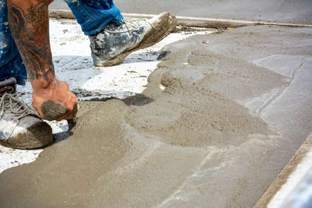 Worker Spreading Building Screed on a Floor of a House during Energy Redevelopment Work on Blurred...