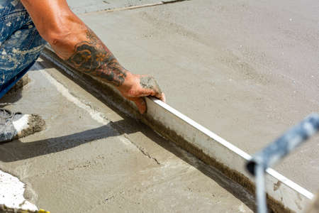 Worker Spreading Building Screed on a Floor of a House during Energy Redevelopment Work on Blurred...