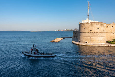 Small Tug thet exits from the Taranto Canalboat in summer, in front of the Aragonese Castle, on...