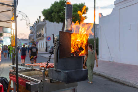 pieces of wood burning in the middle of the street to cook meat during a popular festival in Italy,...