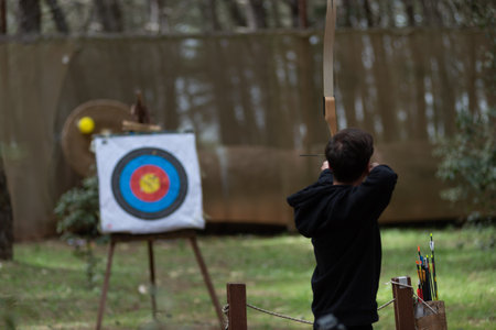 Person Performing Archery In The Forest During An Event On Blurred Backgroundの写真素材