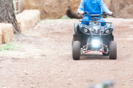Children Riding Quad In The Forest On Holiday Period On Blurred Backgroundの写真素材