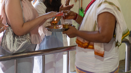 Hindu Believers Praying And Receiving Communion By The Hindu Priest On Blurred Backgroundの写真素材