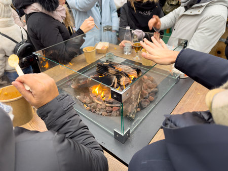 People Eating Around a Street Fireplace In Winter In the North Of Italy During Christmas Period On...