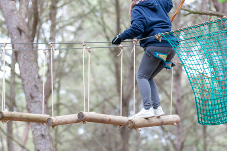 Girl Performing Adventure Path In The Adventure Park In The Forest On Blurred Backgroundの写真素材