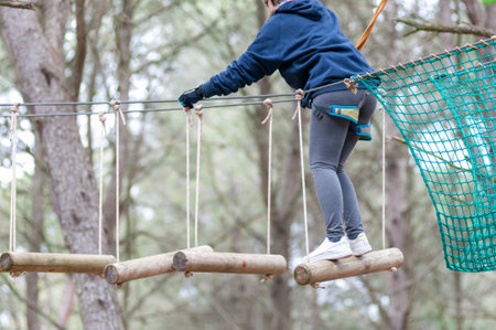 Girl Performing Adventure Path In The Adventure Park In The Forest On Blurred Backgroundの写真素材