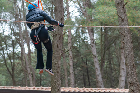 Girl Performing Adventure Path In The Adventure Park In The Forest On Blurred Backgroundの写真素材