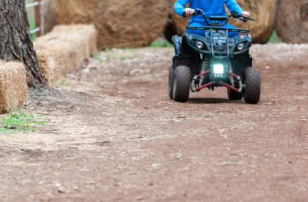 Children Riding Quad In The Forest On Holyday Period On Blurred Backgroundの写真素材