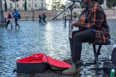 Man Playing Guitar in the Street in Italy Who Asks for Alms On Blurred Background