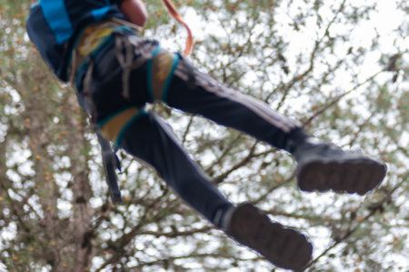Blurred Picture Of Man Hanged At A Steel Rope In The Adventure Park In The Forest In Summerの写真素材
