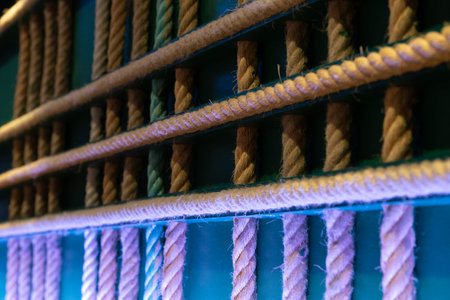Crossed ropes hanging on the wall as an abstract decoration. Home made original interior design with green background and coloufsul led lights, the ropes are made in natural fiber.の写真素材