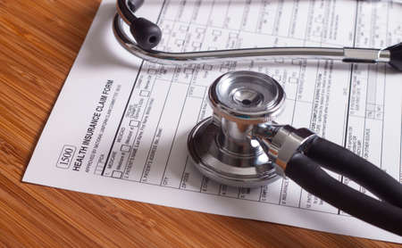 Stethoscope and pen resting on a sheet of medical insurance recordsの写真素材