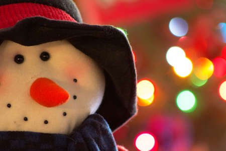 A snowman with a sign of happy holidays with christmas tree behindの写真素材