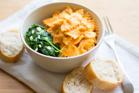 Pasta with white cashew based sauce and red tomatoes sauce with sauteed spinachの写真素材