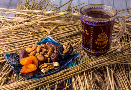 Coffee with dried fruit on straw, on wooden tableの写真素材