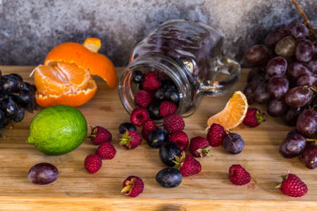 Smoothie jar shape fruits. Grapes, raspberry, lime, dark background