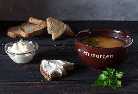 Soup in a bowl with sour cream, herbs and bread on a wooden table.の写真素材