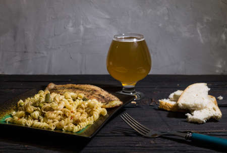 Pasta with delicious, juicy fish, beer and bread on wooden backgroundの写真素材