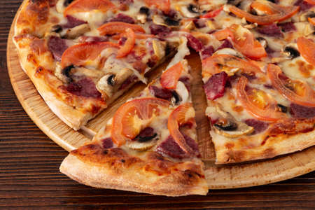 Bavarian pizza with sausages and mushrooms, juicy tomatoes and Parmesanの写真素材