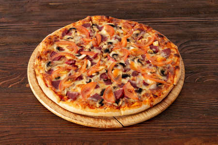 Bavarian pizza with sausages and mushrooms, juicy tomatoes and Parmesanの写真素材