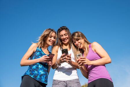 Three happy young women watching the smart phone with a blue sky