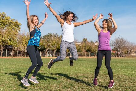 Three young people jumping and having fun together outdoors in sunny day. Health and Lifestyle...