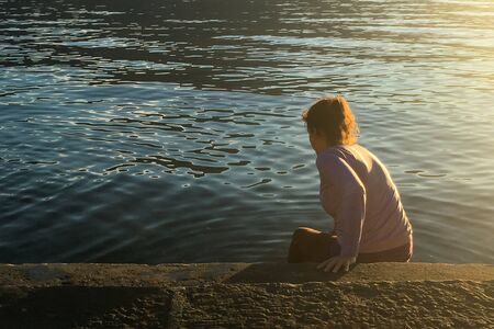 Young woman walking in the lake water at sunset. Life style concept.