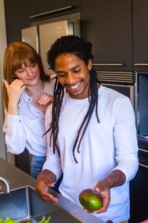 Stock vertical photo of a black guy with dreadlocks smiling with a mango in his hand next to a girlの写真素材