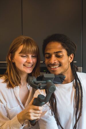 Stock vertical photo of a couple looking at the mobile in the kitchen holding the mobile with a handleの写真素材