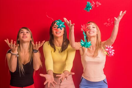 Stock photo of three girls with gift adorns in their hands on a red backgroundの写真素材