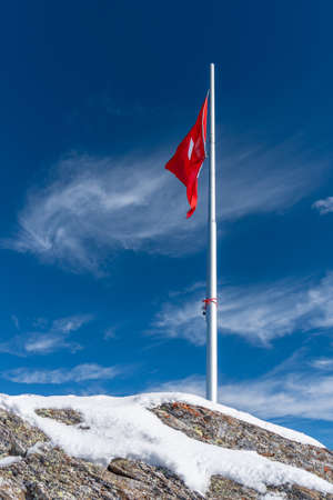 The flag of Switzerland on a flagpole in Diablerets glacier at 3000 meters above sea level in...