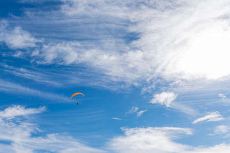 A person doing paraglider on a blue sky with clouds in Diablerets glacier at 3000 meters above sea level in Switzerlandの写真素材
