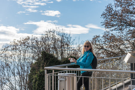 Adult woman with sunglasses smiling and looking at camera with smartphone in hand at the viewpoint of Mont Pelerin,の写真素材