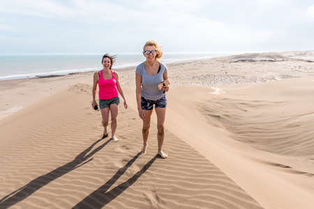Frontal view of two women walking on top of a large dune. Mother and daughterの写真素材