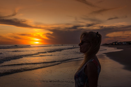 Relaxed woman watching the sunset on the beach. Summer and vacation concept.の写真素材