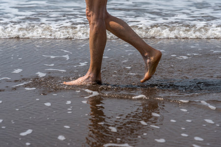 Barefoot woman walking on the seashore at the beach.の写真素材