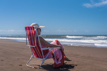 Mature woman relaxing sitting on a beach chair at the beach. Summer concept.の写真素材