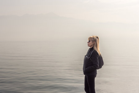 Traveler mature woman standing outdoors in nature on a foggy day.の写真素材