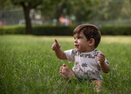 Cute baby boy pointing somewhere while enjoying the day outdoors in a park.の写真素材