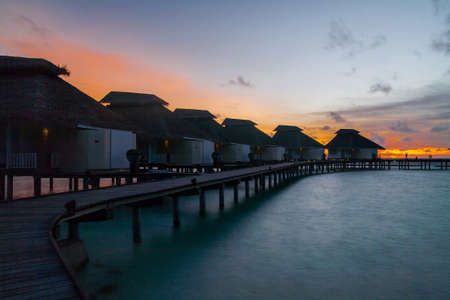 Sunset on tropical Maldives island, water villas resort. Waterhuts at sunset