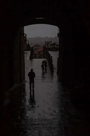Silhouette of two people walking in the street of the old townの写真素材