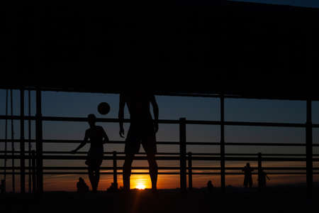 Silhouette of people playing soccer at sunset.の写真素材