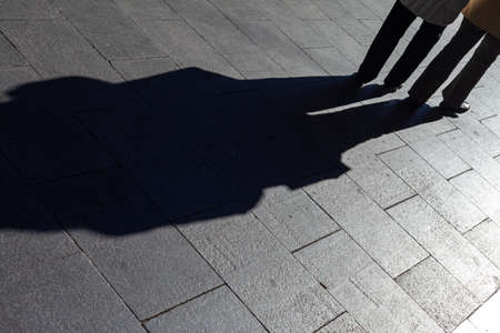 Long shadow of a man and a woman on the pavement in the city