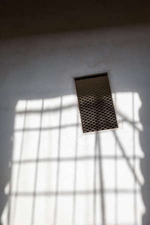 Window with a lattice on a white wall. Sunlight through the window.の写真素材